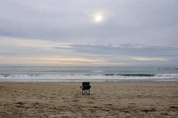 single chair on an empty beach late in afternoon
