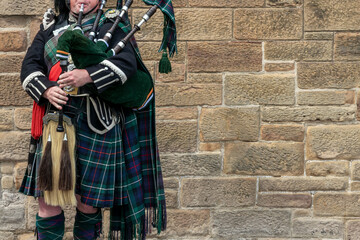 Scottish bagpiper dressed in traditional kilt in Edinburgh, Scotland (with copy space) - obrazy, fototapety, plakaty