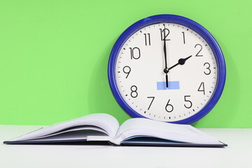 Wall clock with green background, open agenda white sheet.