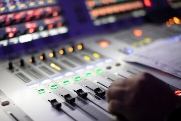 The sound engineer's hands move the sliders of the device.