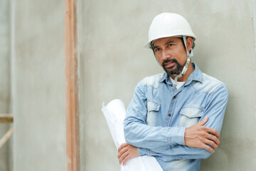 Engineer architect manager foreman Indian man long sleeve denim shirt Standing with arms crossed, holding diagram of the building's structure. Then he changed his posture and placed hands sides.