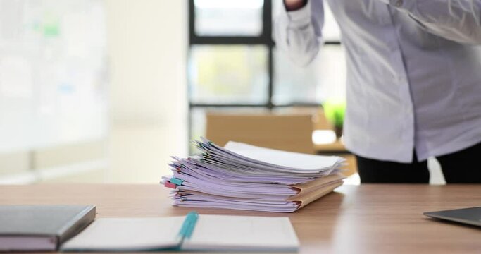 Secretary places stack of project documents on table in office