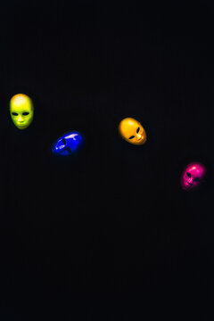 Different colorful carnival masks scattered on a black background.