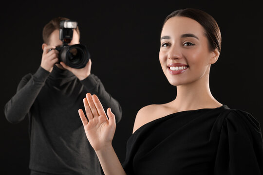 Photographer taking picture of beautiful woman on black background, selective focus