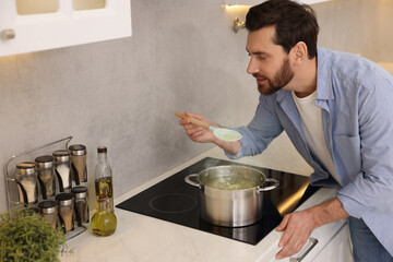 Man cooking delicious chicken soup in kitchen