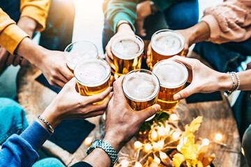 Fototapeta na wymiar Group of friends drinking and toasting beer at brewery bar restaurant - Friendship concept with people enjoying happy hour sitting at bar table - Close up image of brew glasses