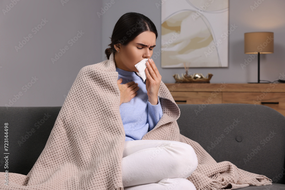 Sticker Woman coughing with tissue on sofa at home. Cold symptoms