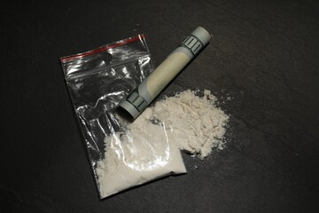 Drug addiction. Plastic bag with cocaine and rolled dollar banknote on grey textured background,,...
