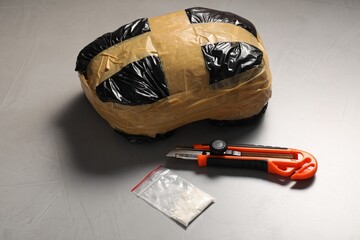 Packages with narcotics and stationery knife on grey textured table