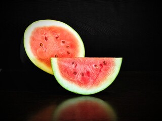 Two slices of watermelon against a dark backdrop