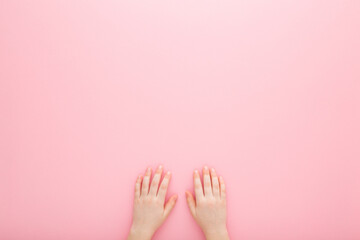 Little girl hands on light pink table background. Pastel color. Closeup. Point of view shot. Empty place for text. Top down view. - obrazy, fototapety, plakaty