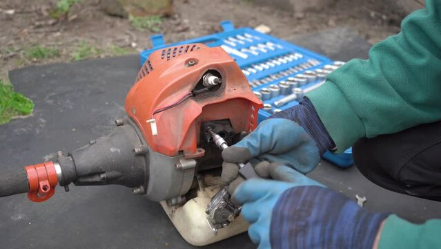 a man disassembles a mower,a man with a screwdriver disassembles a mower