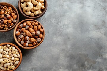 Assorted nuts in wooden and clay bowls featuring hazelnuts cashews almonds and walnuts placed on a gray background with a blank area Banner included