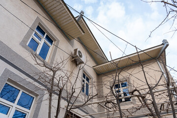 Obraz premium a two floor home with a ventilator and air conditioner outdoor unit with multiple blue windows and sky