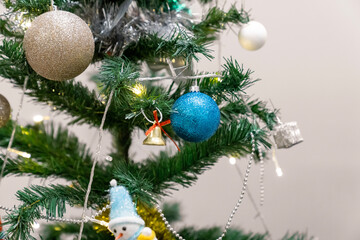 Christmas composition, gold and silver baubles, bows, animals, bells, lit garlands on a festive xmas fir tree against the decorative brick wall background. Copy space. Winter holidays concept.