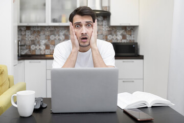 Close up portrait of shocked man with bugged eyes looking at laptop	