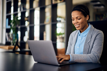 A smiling African businesswoman, working over the laptop at the office.