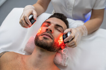 Obraz na płótnie Canvas Dark-haired bearded man receiving phototherapy in a clinic