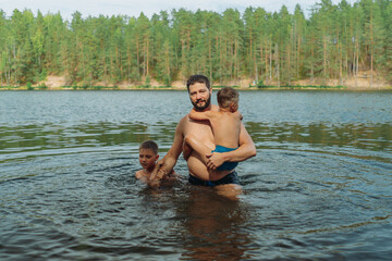 father and children swimming in forest lake. Man teaching son to swim