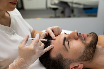 Obraz na płótnie Canvas Dark-haired bearded man having session of mesotherapy in a beauty salon
