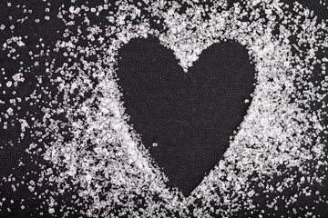 White sugar heart shaped on black background
