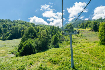 Cable car seats soar over beautiful mountains on a sunny day in Krasnaya Polyana