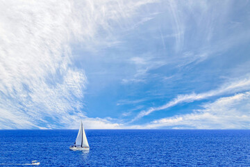 Boat, sailboat sailing on the beach of Mallorca under a blue sky with white clouds	