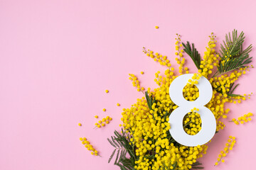 International Women Day on 8 March celebration with fresh spring mimosa flowers and number eight top view. Beautiful holiday pink greeting background with copy space.
