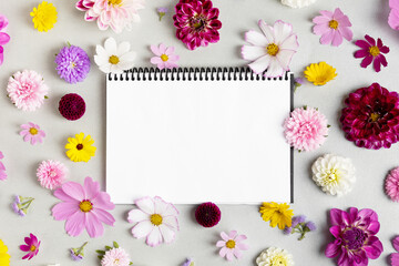 Creative layout made of flowers asters, dahlias, calendula and notebook with clean page. Birthday...