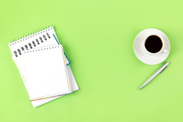 Composition with opened blank notepad and pen, cup of black coffee on a green background. Hello spring