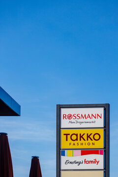 Firmenlogos der Marken ROSSMANN Mein Drogeriemarkt, TAKKO FASHION und Ernsting's family an einem Industriegebiet als Hinweisschild / Wegweiser.