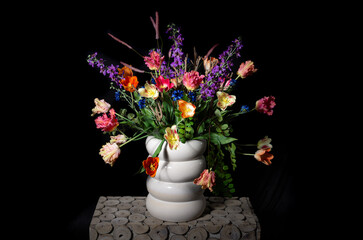 flower arrangement with colored silk flowers in vase. Black background. Studio photo.