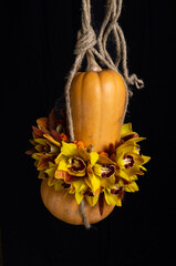 pumpkin hanging on rustic rope with decorative yellow orchids