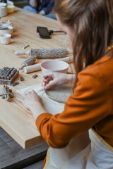 Hand moulding from white clay, Potter moulding an openwork plate. A woman potter in the workshop passionately moulding a product. - obrazy, fototapety, plakaty