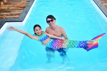 pai com filha vestida de sereia em piscina , alegria no verão 