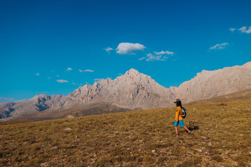 little boy with a backpack walks along a path against the backdrop of mountains. travel with children to the mountains. Turkey. Aladaglar.