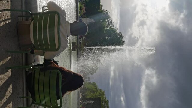 Multi-ethnic People Sitting in Front of Fountain at the Jardin des Tuileries. a couple of lovers sits in front of a fountain in France, a man and a woman look at the fountain in the park,