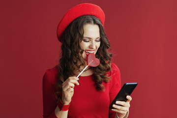 Naklejka premium woman isolated on background with heart shaped candy using phone