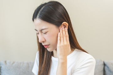 Tinnitus concept, sick asian young woman, girl have ear pain or earache, hand touch plug ear, suffering painful otitis from loud of noisy sound, inflammation. Health care nerve deaf eardrum disease.
