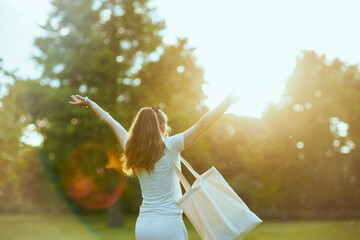 smiling stylish female in white shirt with tote bag rejoicing