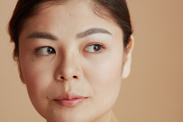 young asian woman looking sideway on beige background