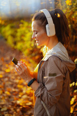 elegant woman in fitness clothes in park with headphones