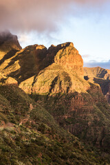 Mountains of Masca Valley at golden hour with a beautiful rainbow. Tenerife, Canary Islands, Spain. Vertical framing. - 723195491