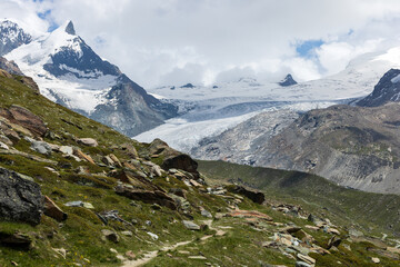 Alpine mountain view with snowy peaks and hiking trails from Rothorn covered with clouds