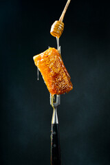 Honey stick and Honeycombs on a metal fork. Macro photo. Organic honey.