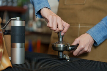 The hands of an Asian female employee Barita employee Businessman cafe owner coffee bean press being used make coffee into lumps making coffee Next coffee maker equipment The shop small business