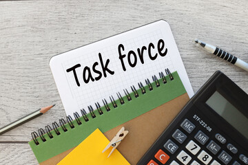 TASK FORCE notepad with spring with text. wood background