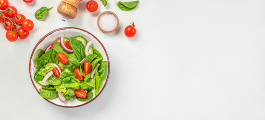 vegetable salad of fresh tomato, cucumber, onion, spinach and lettuce on a white background....