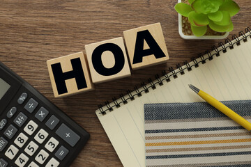 HOA text on wooden blocks. near a potted plant and a calculator