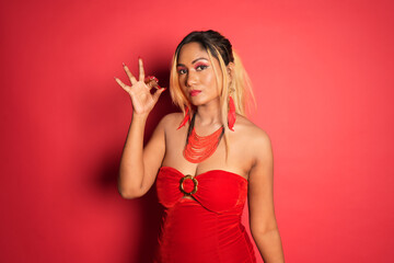 a woman with red dress showing the peace sign while standing on a red wall